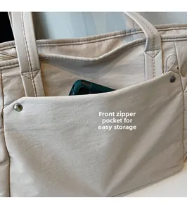 Vue détaillée de la poche avant zippée sur un grand sac cabas en toile beige très pratique