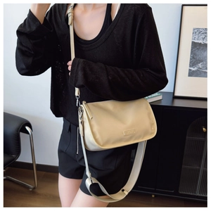 Sac à bandoulière beige chic avec large sangle dans un intérieur minimaliste