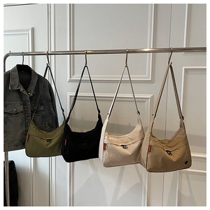 Macro detail of large nylon hobo bags in four colors hanging on a metal rack