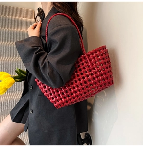 Detail of a bright red woven handbag with intricate mesh texture and matching strap