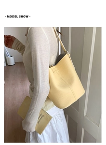 Close-up of yellow lychee pattern leather bucket bag with brand tag detail
