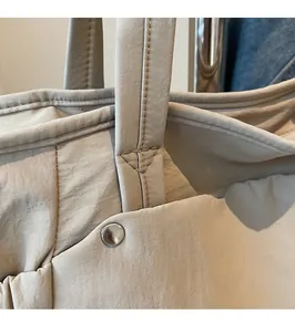 Gros plan des coutures renforcées et des boucles en argent du sac cabas en nylon