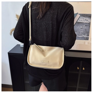 Détail du sac polochon en toile beige minimaliste avec étiquette de marque et bandoulière