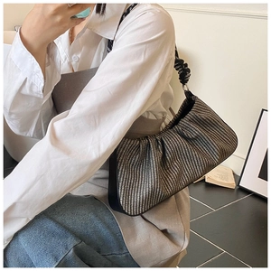 Detail of woven texture and knotted strap on the black and white pleated cloud bag