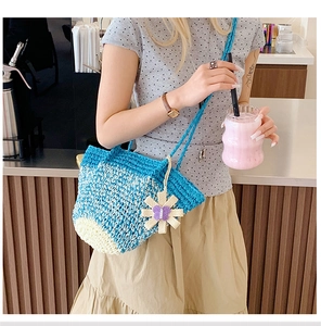 Detail of blue and beige crochet tote bag with a decorative floral butterfly charm