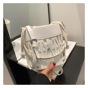 Detail of white hollowed bucket bag with laser-cut patterns and silver rivet studs