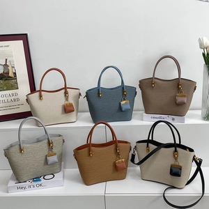 Collection of textured tote bags in six colors with mini pouch charms in a lifestyle setting