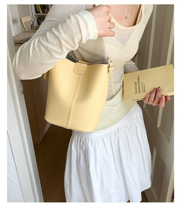 Detail of light yellow leather bucket bag featuring lychee texture and adjustable strap