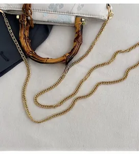 Detailed shot of bamboo style handle and gold chain strap on floral lace handbag