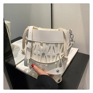Detailed shot of white hollow-out bucket bag with silver studs and canvas drawstring insert