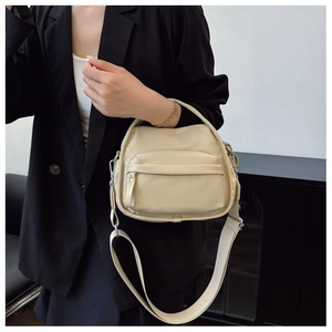 Detail of beige crossbody bag with adjustable wide fabric strap and front zipper pocket