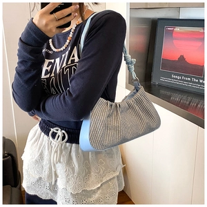 Detail of blue leather strap with knot design and woven fabric texture on a shoulder bag