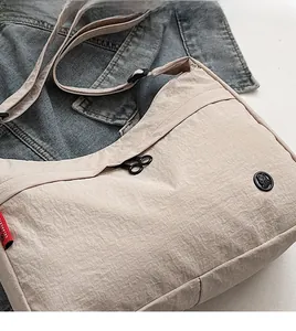 Detail of beige nylon shoulder bag with crinkle texture on denim background