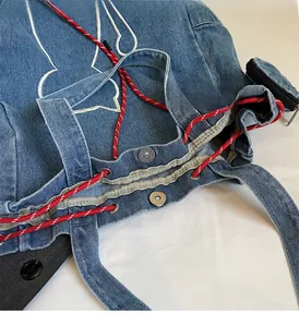 Detail view of denim tote bag featuring white embroidery and durable metallic hardware