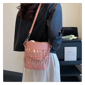 Detailed shot of pink hollow-out bucket bag with rivets and beige drawstring inner pouch