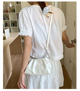 Detailed view of white pleated cloud bag with soft faux leather and crossbody strap