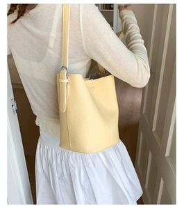 Detail of light yellow bucket bag with lychee grain texture and adjustable strap