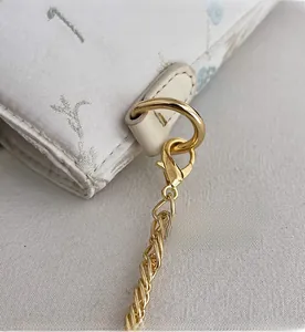 Close-up of durable golden metal hardware and lobster clasp on floral fabric bag