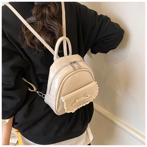Detail eines cremefarbenen Mini-Rucksacks mit Schleife und Spitze aus 45-Grad-Winkel