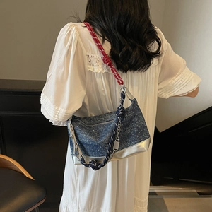 Detail of blue denim tote bag with silver leather bottom and woven rope straps