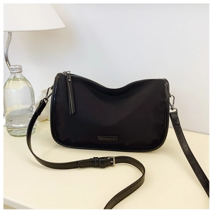 Détail du sac polochon en nylon noir avec bandoulière réglable et logo métallique