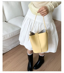 Close-up of lemon yellow bucket bag with lychee grain texture and metal hardware
