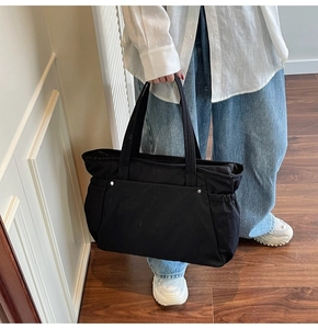 Détail d'un grand sac cabas en toile noire avec rivets argentés et poches latérales