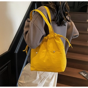 Detail of bright yellow nylon tote bag with drawstring closure and silver metal accents