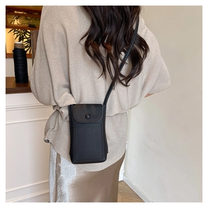 Model wearing a black lychee texture mini crossbody phone bag with a flap closure