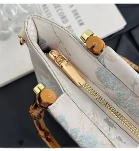 Detail of smooth gold zipper and bamboo handle on light blue printed fabric handbag