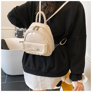 Detail eines Mini-Rucksacks in Creme mit Spitzenbesatz und süßer Schleife