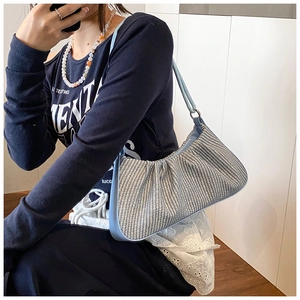 Detail view of light blue woven texture with gathered pleat design on the hobo bag