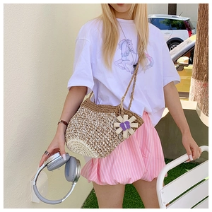 Detail of handmade straw shoulder bag with woven flower charm for summer vacation