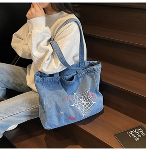 Detailed close-up of blue denim tote bag with spider web and spider embroidery