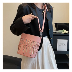 Detail of pink hollow-out bucket bag with silver studs and a drawstring inner pouch