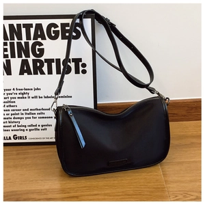 Détail d'un sac bandoulière noir en forme de croissant avec finition mate et sangle réglable