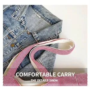 Détail de sac en toile à rayures rouges et blanches près d'un col en jean bleu