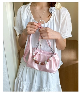 Detail of pink pleated bucket bag with metallic finish and beaded handle charm