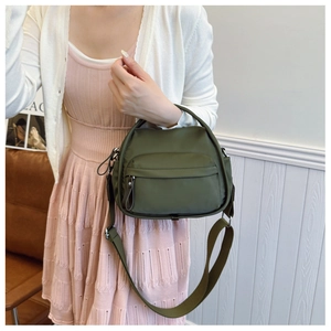 Detail of army green nylon crossbody bag with front zipper pocket and adjustable strap