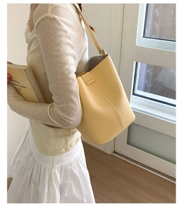 Detail view of bright yellow litchi grain leather bucket bag with slim shoulder strap
