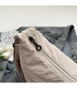 Detailed macro view of high-quality smooth metal zipper on beige nylon shoulder bag