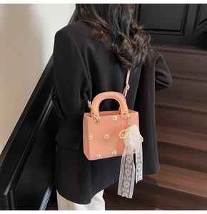 Pink daisy embroidery crossbody bag detail with lace pearl pendant on black blazer