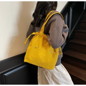 Bright yellow nylon tote bag side view showing large capacity and drawstring closure detail