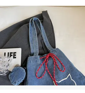 Detail of denim tote bag showing red braided drawstring and white cat embroidery
