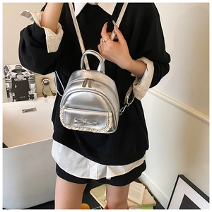 Detail eines silbernen Metallic-Mini-Rucksacks mit weißer Spitze und Schleifenverzierung