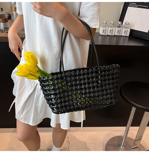 Detail of black hollow out woven beach tote with long handles and tulip decorations