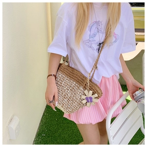 Detail of woven straw bag showing texture and decorative flower charm with strap