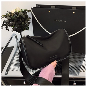 Détail du sac bandoulière en nylon noir avec large sangle et fermeture éclair argentée