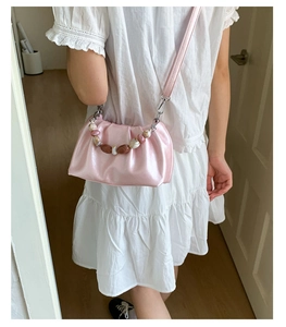 Detail of pink ruched cloud bag featuring glossy finish and beaded top handle