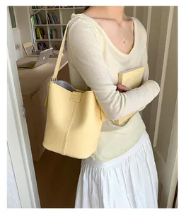 Detail of light yellow pebble grain leather bucket bag featuring a sleek metal buckle closure